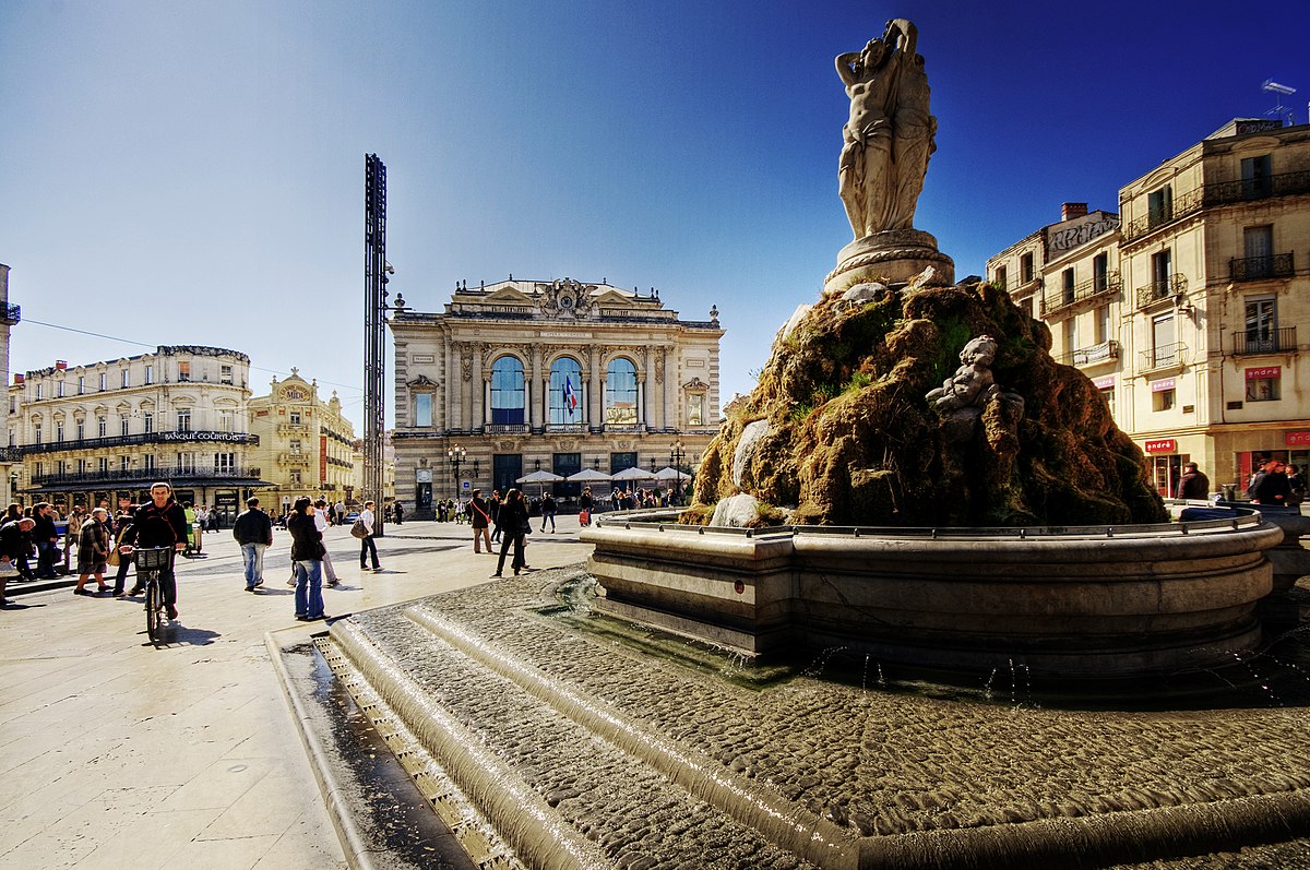 Vibrant urban square with historic architecture and a central fountain, used to represent the Montpellier district of Cheltenham.