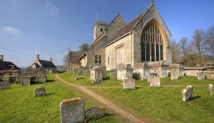 St Mary’s Church in Swinbrook with historic gravestones and a stone path leading through the churchyard