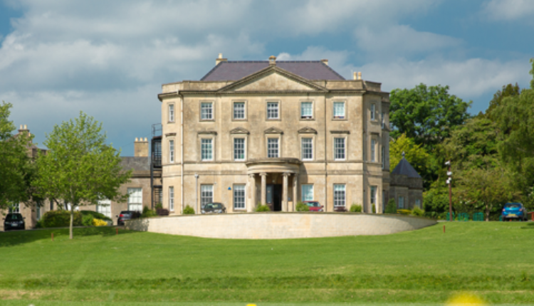 Elegant Georgian mansion at Hardenhuish House set within landscaped lawns under a partly cloudy sky