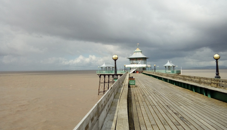 Clevedon Pier extending over the Bristol Channel with wooden decking and Victorian pavilion under cloudy skies