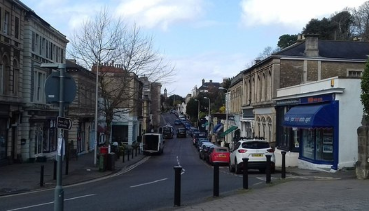Hill Road in Clevedon with parked cars, local shops, and historic stone buildings lining the street