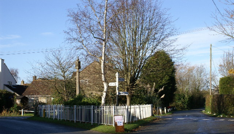 Village crossroads with trees, cottages, and signposts in Kingston Seymour, North Somerset