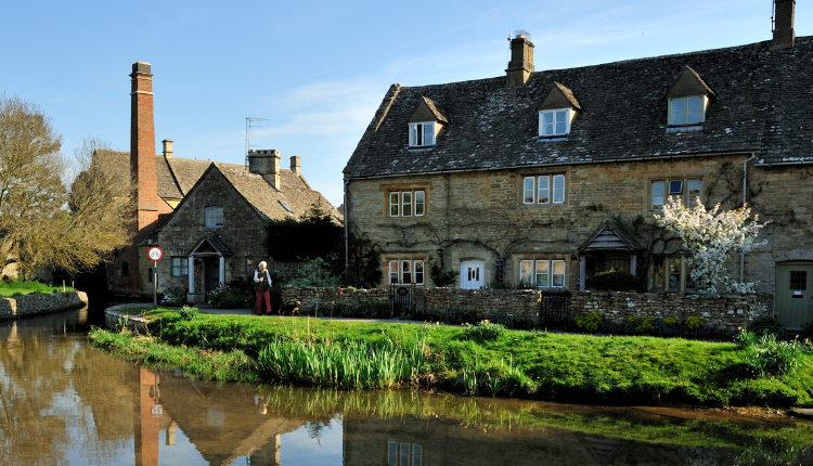 Stone cottages reflected in the River Eye at Lower Slaughter in the Cotswolds