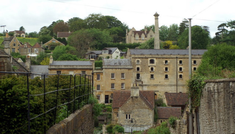 Traditional stone buildings and historic mill structures in Freshford village surrounded by green countryside in Somerset