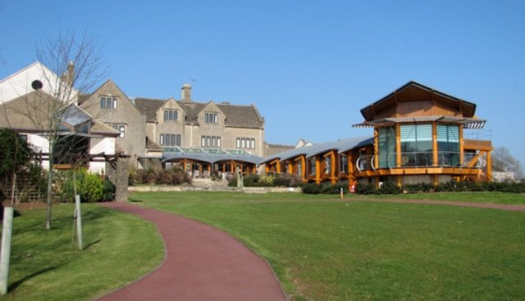 Modern community buildings and traditional stone houses set around green open space in Winsley village near Bradford-on-Avon