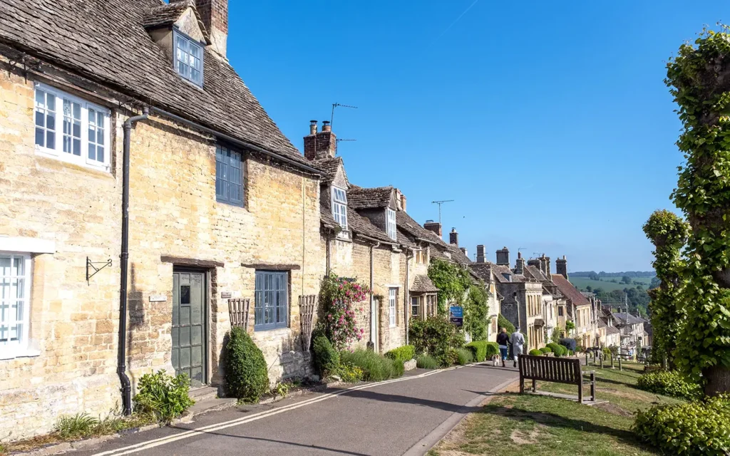 Cotswold stone cottages along Burford High Street on a sunny day, showcasing the historic charm of Burford in the Cotswolds