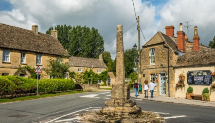 Stone village crossroads in Ashton Keynes with historic cottages and a traditional pub in the background.
