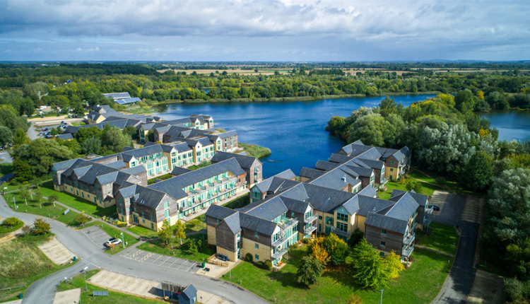 Aerial view of South Cerney with modern lakeside homes set beside the Cotswold Water Park and surrounding countryside.