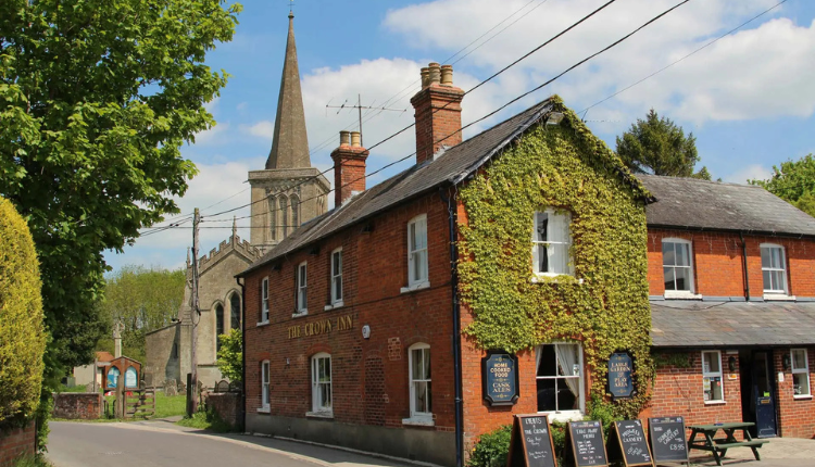 Traditional red-brick building in Bishop’s Cannings, Wiltshire, with ivy-covered walls and village church in the background