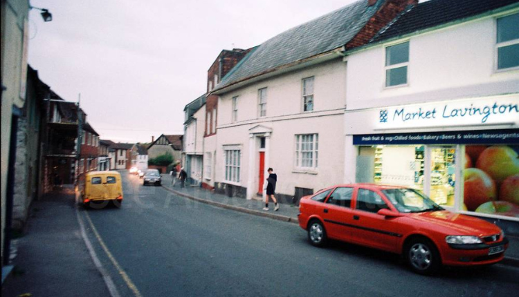 Street view of Market Lavington village with traditional buildings, parked cars and local shops