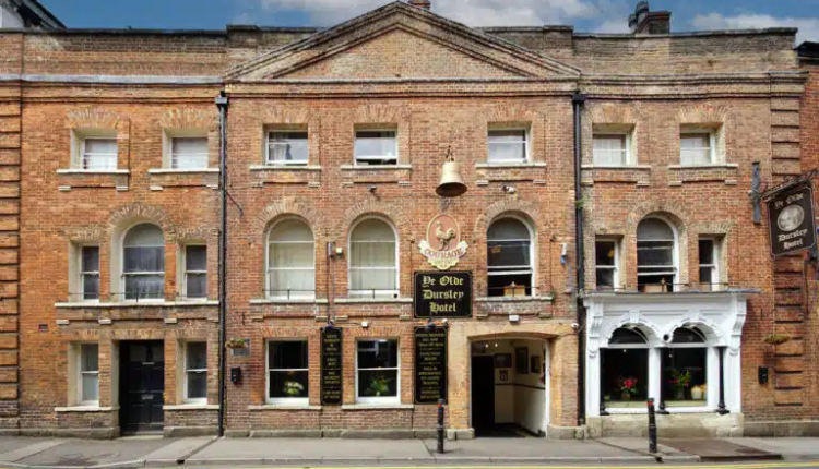 Historic frontage of The Old Bell Inn in Dursley, a traditional brick-built coaching inn with arched windows and classic English pub signage.