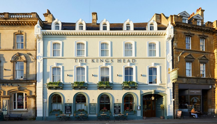Front exterior of The Kings Head in Wotton-under-Edge, a historic town-centre hotel with a pale blue façade and arched ground-floor windows.