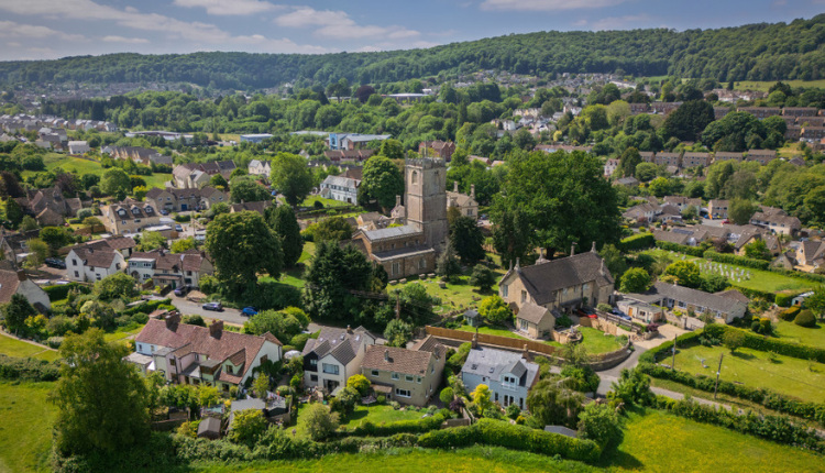 Aerial view of Cam in Gloucestershire, showing houses, green hills, and the village church.