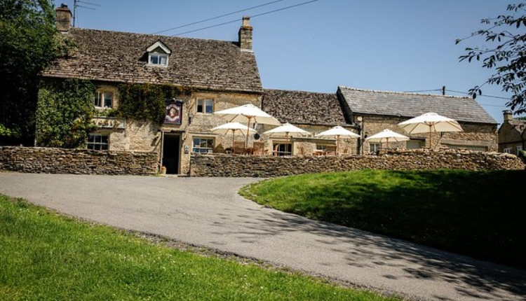 Cotswold stone inn with outdoor seating in the village of Eastleach.