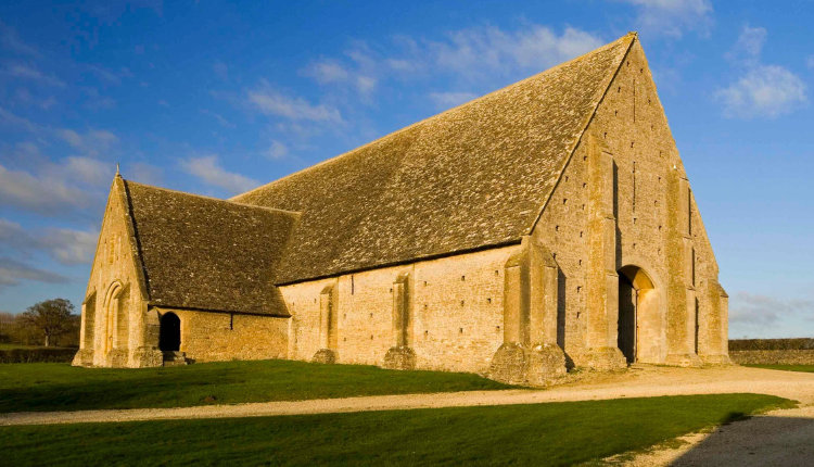 Great Coxwell Barn near Faringdon, a large medieval stone tithe barn with a steep pitched roof set in open countryside.